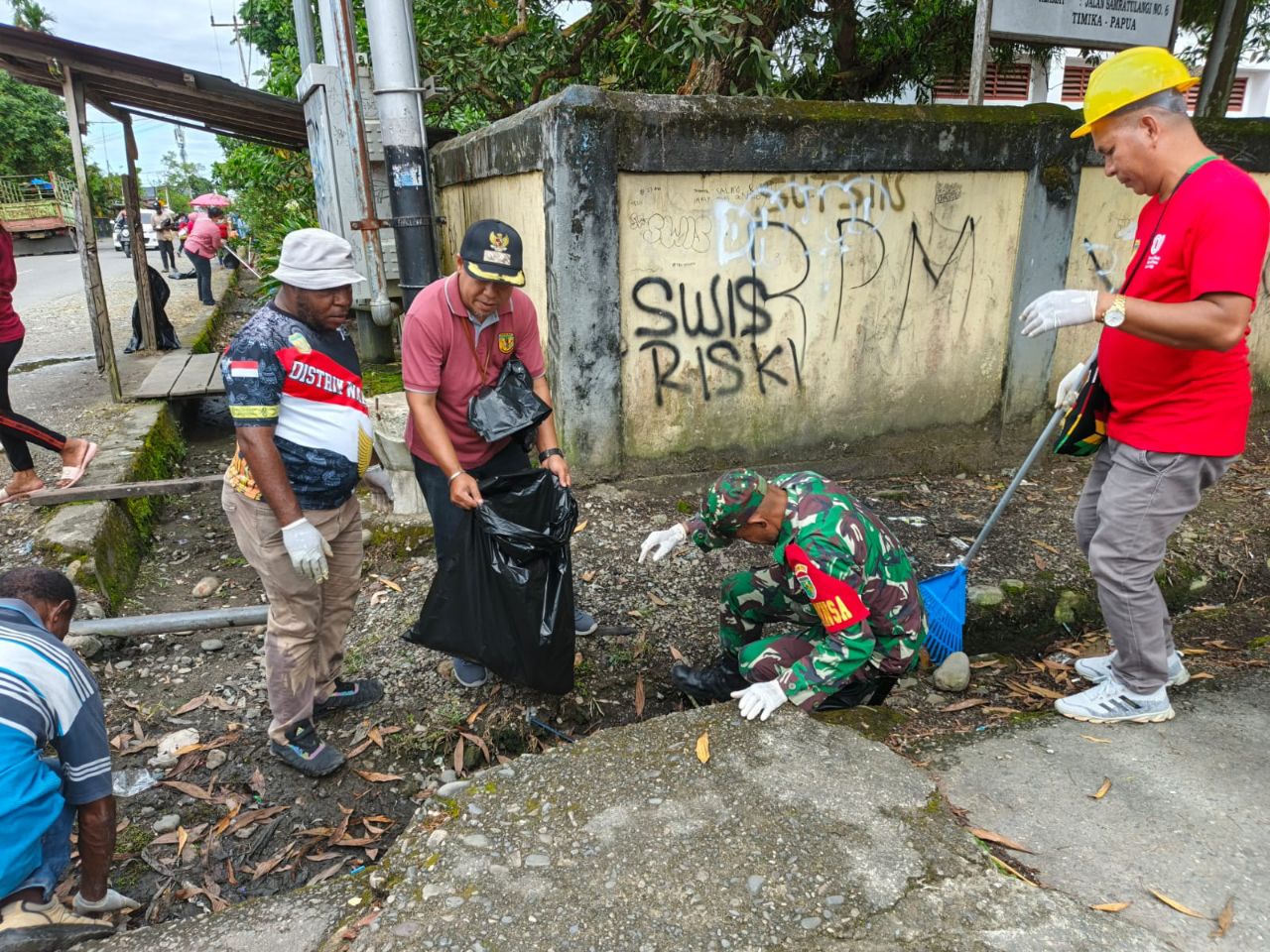Mencegah Terjadinya Sumbatan Dan Genangan Air, Babinsa Koramil Timika Ajak Warga Bersihkan Saluran Drainase